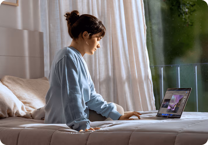 A woman working on her HP laptop in bed.