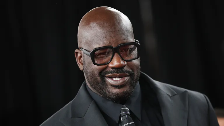 Shaquille O'Neal wearing black glasses and a black suit.